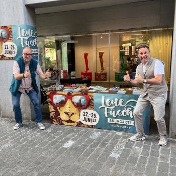 Foto zweier Festbändel-Verkäufer vor ihrem Marktstand. Foto zweier Festbändel-Verkäufer vor ihrem Marktstand.
